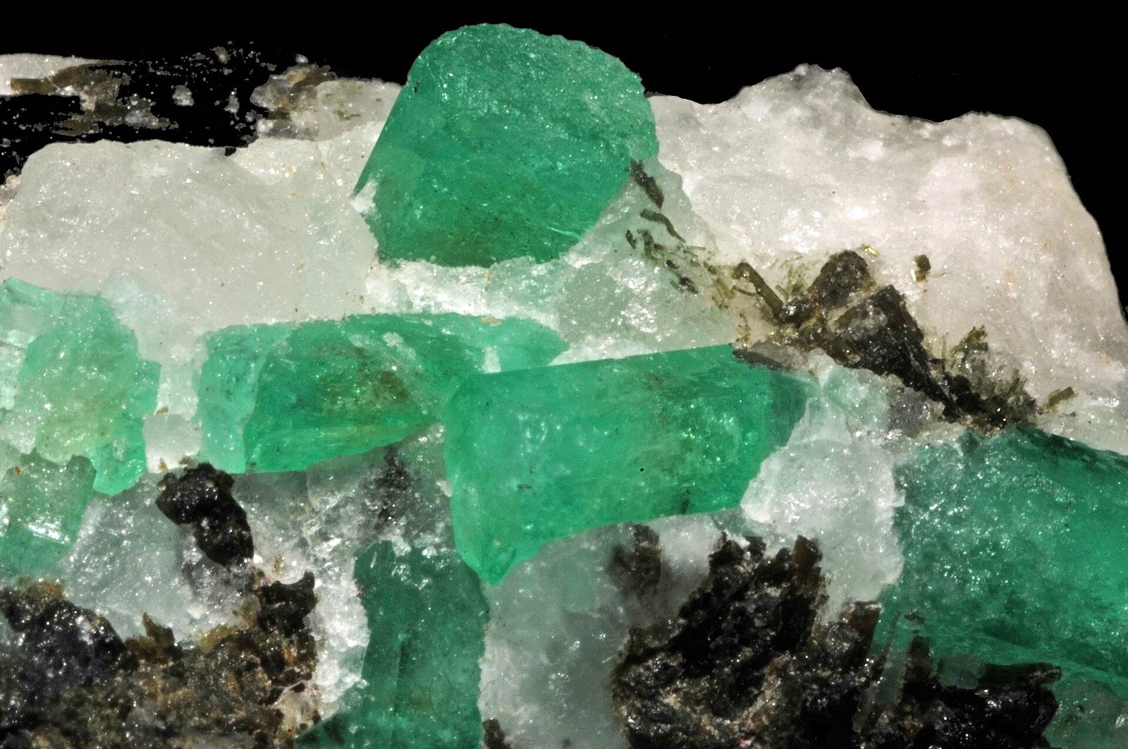 Emerald crystals set in white host rock with dark tourmaline, from the Mingora mine in Swat